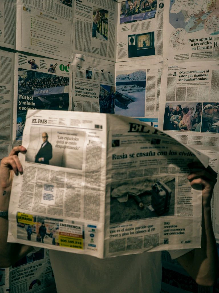 An editor marking proofs at a desk lamp inside the X-News newsroom.